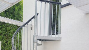 Uma escada em caracol com guarda-corpos de metal e uma porta de garagem ao fundo.