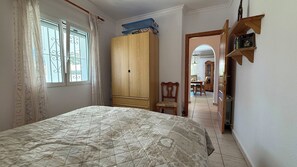 Een slaapkamer met een bed, een kledingkast, een stoel en een boekenkast.