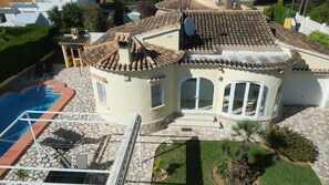 Een villa in mediterrane stijl met een zwembad, een overdekt terras en een verzorgde tuin.