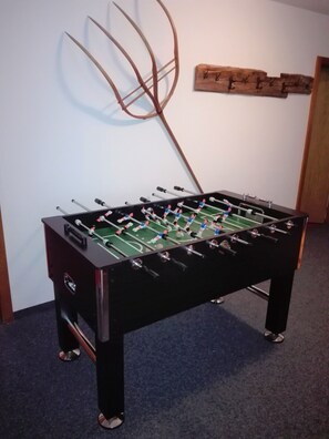 A foosball table in a room with a carpeted floor and a wooden wall decoration.