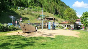 A playground with a large ship-shaped play structure, a café, and a building with a red roof.