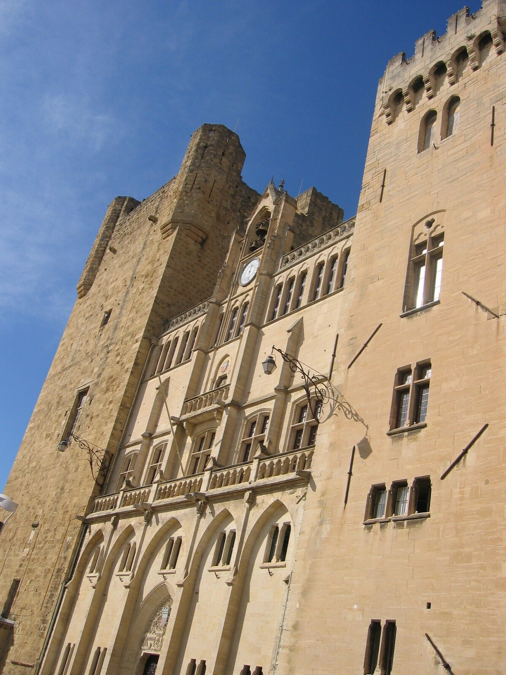 Un edificio histórico con una torre de reloj, ventanas arqueadas y un balcón con barandillas de hierro forjado.