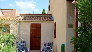 A courtyard with a wooden gate, two lounge chairs, a door, and a satellite dish. - Exclusively furnished apartment, 3 minutes from the beach (Gruissan)