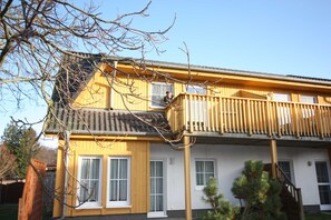 A two-story building with a balcony, a window, and a door.