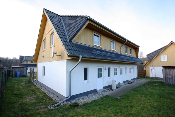 A two-story house with a sloped roof, a front porch, and a small front yard.