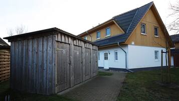 A two-story house with a wooden garage and a paved driveway.