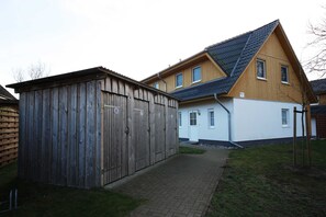 Ein zweistöckiges Haus mit einer Holztgarage und einem gepflasterten Auffahrt.