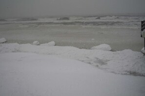 A snowy beach with waves crashing onto the shore.