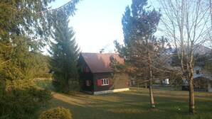 A small house with a red roof and white trim, surrounded by trees and a grassy yard. - cozy house in a sunny place with a fantastic mountain panorama (Bad Mitterndorf)