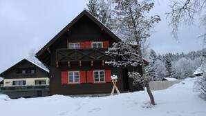 A two-story wooden house with red shutters and a snow-covered landscape. - cozy house in a sunny place with a fantastic mountain panorama (Bad Mitterndorf)