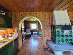A wooden interior with a kitchen, dining area, and a green cabinet with decorative tiles.