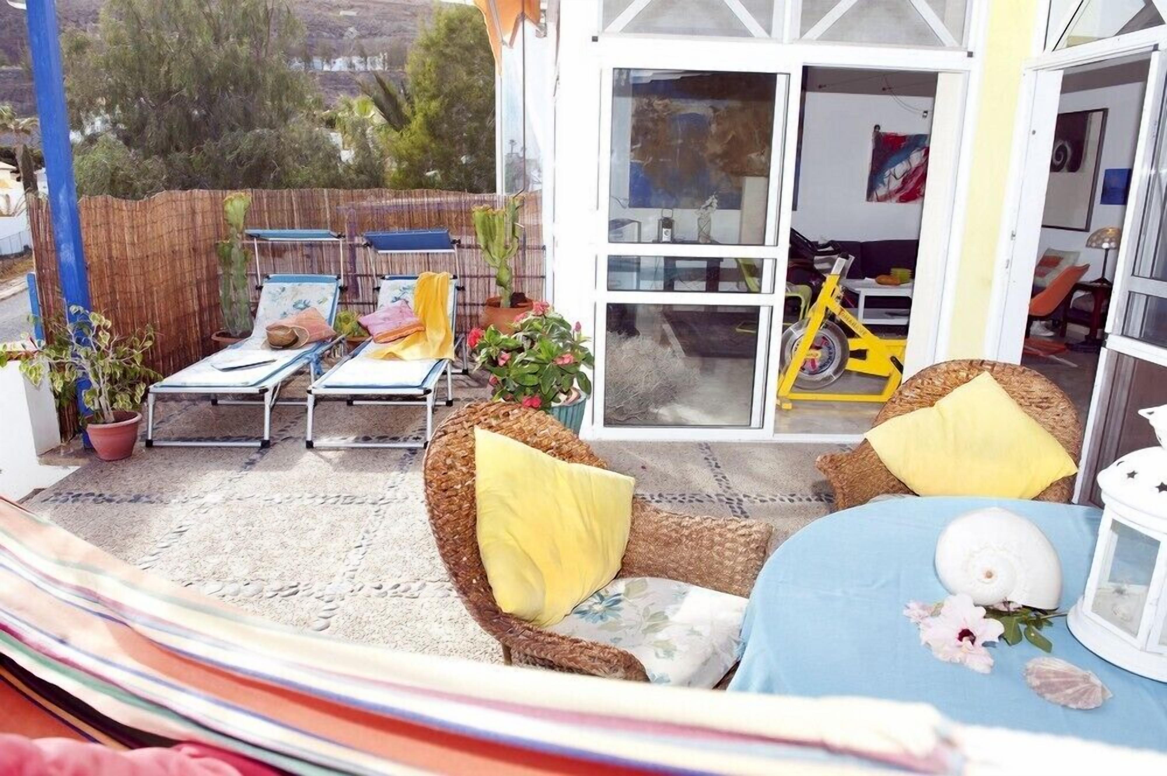 A patio area with wicker furniture, a table with a shell decoration, and a yellow chair.