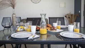 A dining table set for breakfast with plates, glasses, and a pitcher of orange juice. - Beautiful brand new villa ***** with heated swimming pool, summer kitchen, WiFi, grill (Pula)