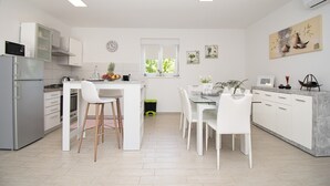 A modern kitchen with white cabinetry, a central island, and a dining area with white chairs. - Beautiful brand new villa ***** with heated swimming pool, summer kitchen, WiFi, grill (Pula)