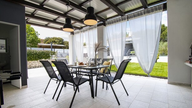 An outdoor patio with a round table, black chairs, and pendant lighting. - Beautiful brand new villa ***** with heated swimming pool, summer kitchen, WiFi, grill (Pula)