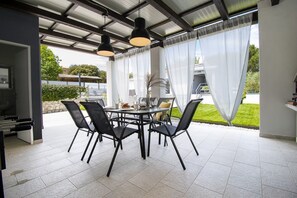 An outdoor patio with a round table, black chairs, and pendant lighting. - Beautiful brand new villa ***** with heated swimming pool, summer kitchen, WiFi, grill (Pula)