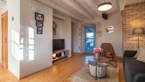 A cozy living room with a wooden floor, a round coffee table, a sofa, and a TV on a wooden stand.