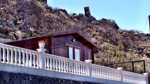 Een houten chalet met balkon, gelegen tegen een rotsachtige helling.