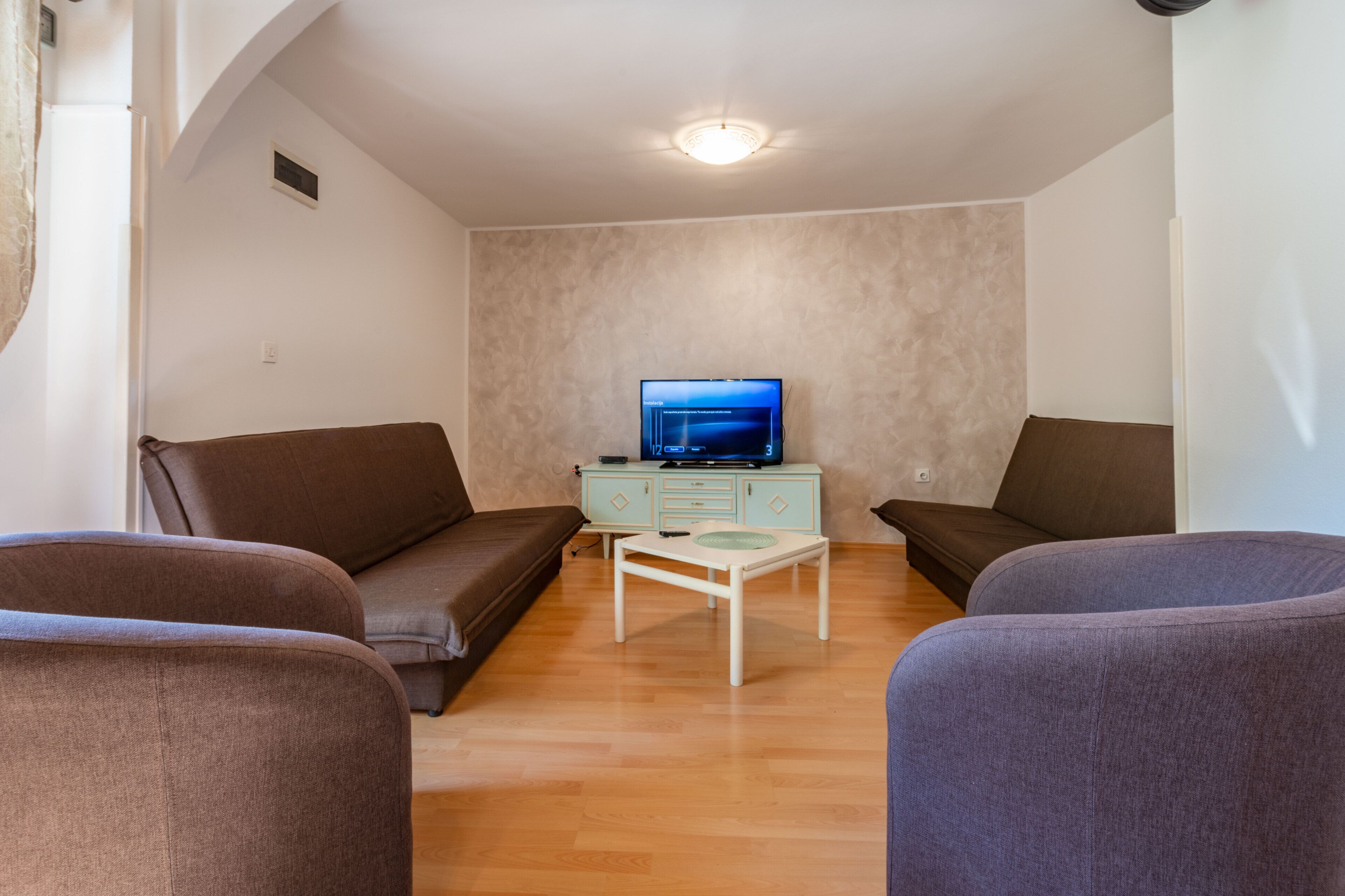 Un salon avec un canapé, une table basse et un téléviseur posé sur un meuble.