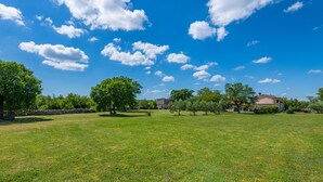 A grassy field with trees and a building in the background. - Quiet and secluded, minutes to beach, private pool in a wonderful garden (Trget)