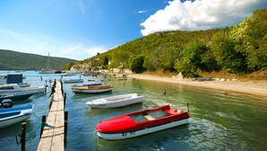 A marina with several boats docked, a wooden pier, and a hillside with greenery and buildings in the background. - Quiet and secluded, minutes to beach, private pool in a wonderful garden (Trget)