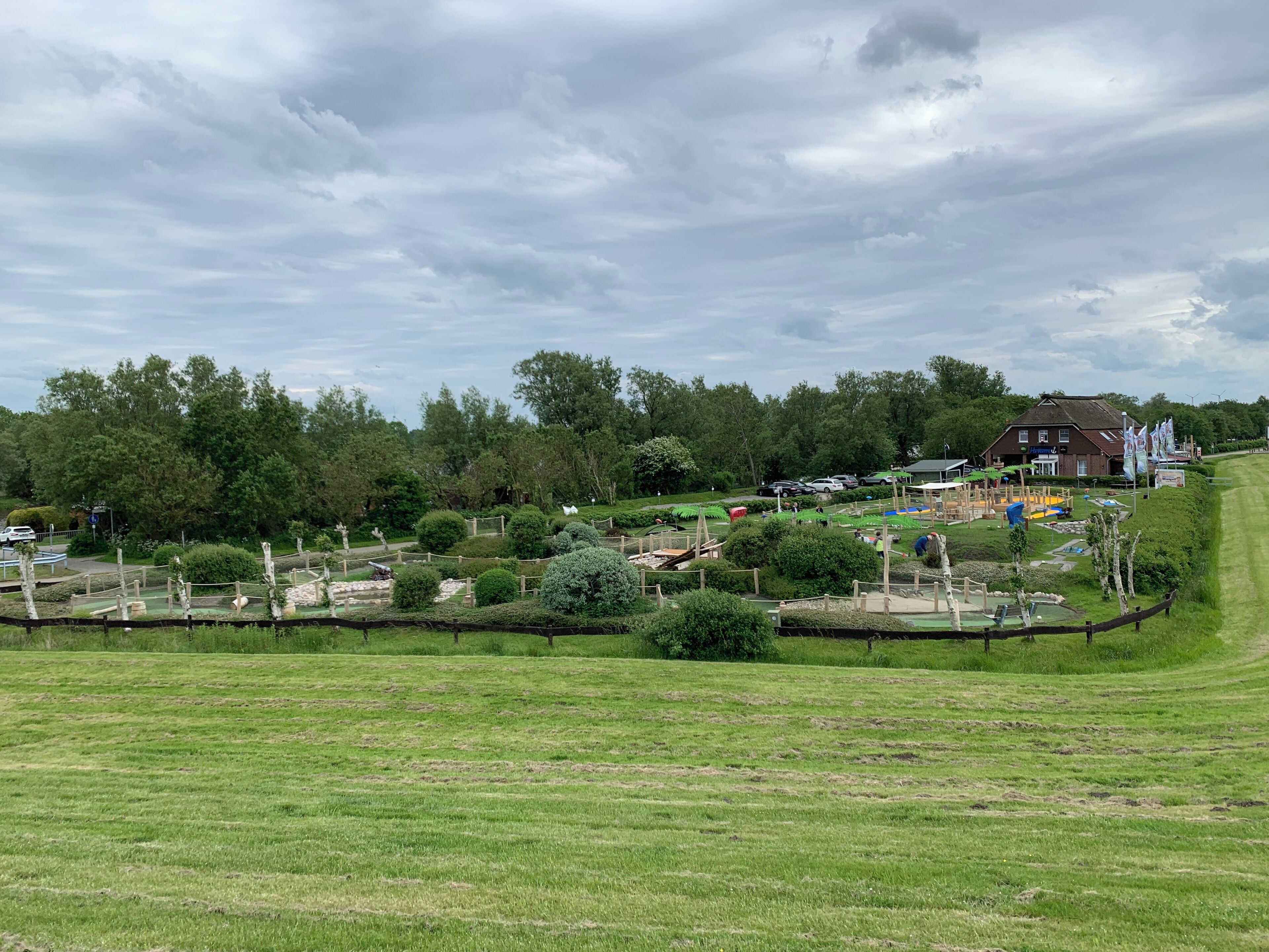 Un parc doté de diverses attractions, notamment une aire de jeux, un petit bâtiment et un espace clos où se trouvent des sculptures.