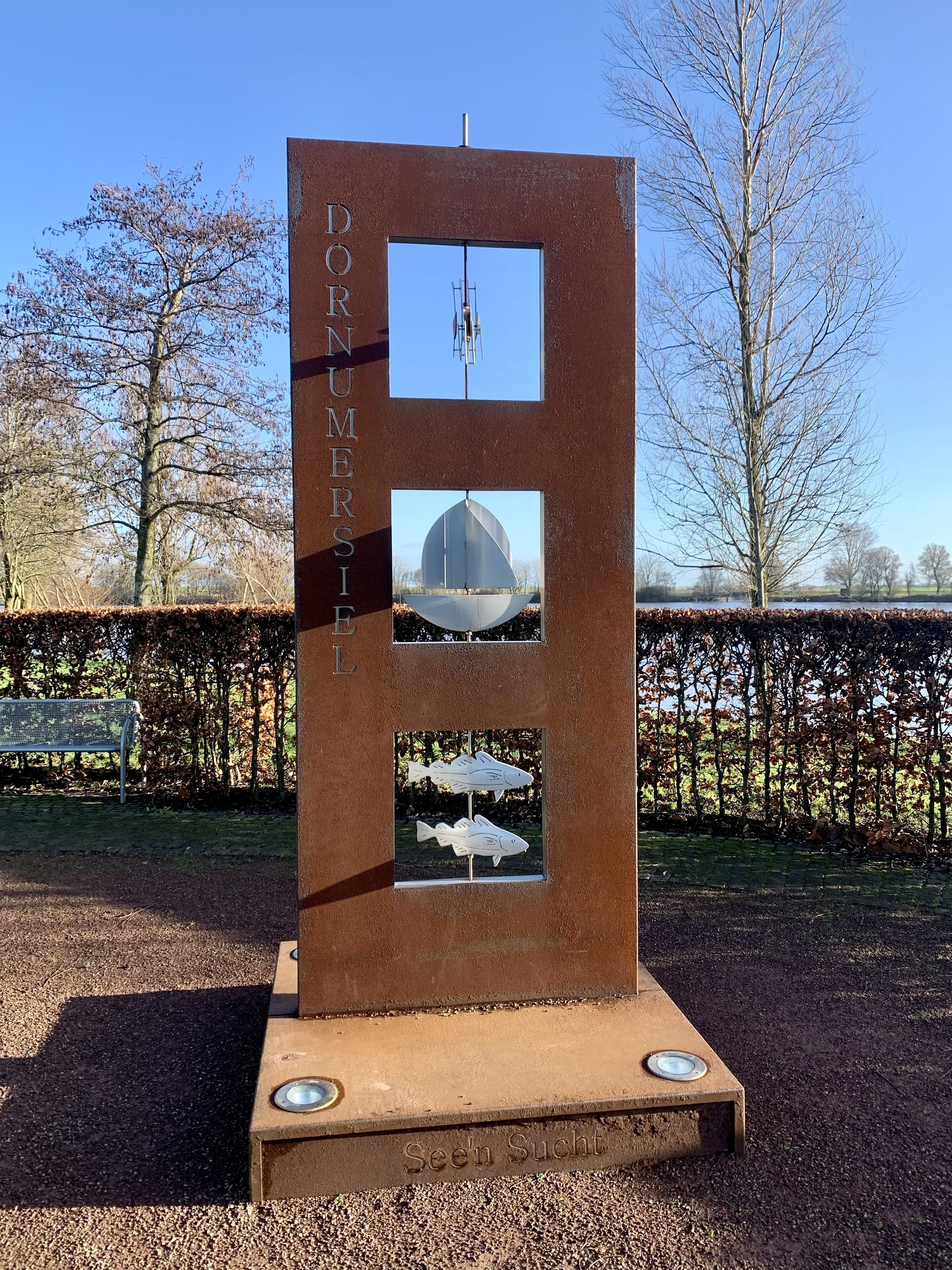 A tall, rectangular metal structure with the inscription "DORNEMERIE" on its side, featuring three square windows displaying different views.