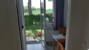 A room with a sliding glass door leading to a patio with a tiled floor, a wooden table, and a chair. - Enjoy stunning views over Kiel and nature (Kiel)