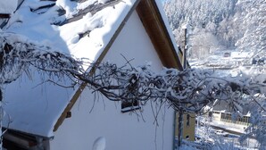 A snow-covered house with a sloped roof and a visible satellite dish. - Comfortable summer cottage in a beautiful surrounding (Marienberg)