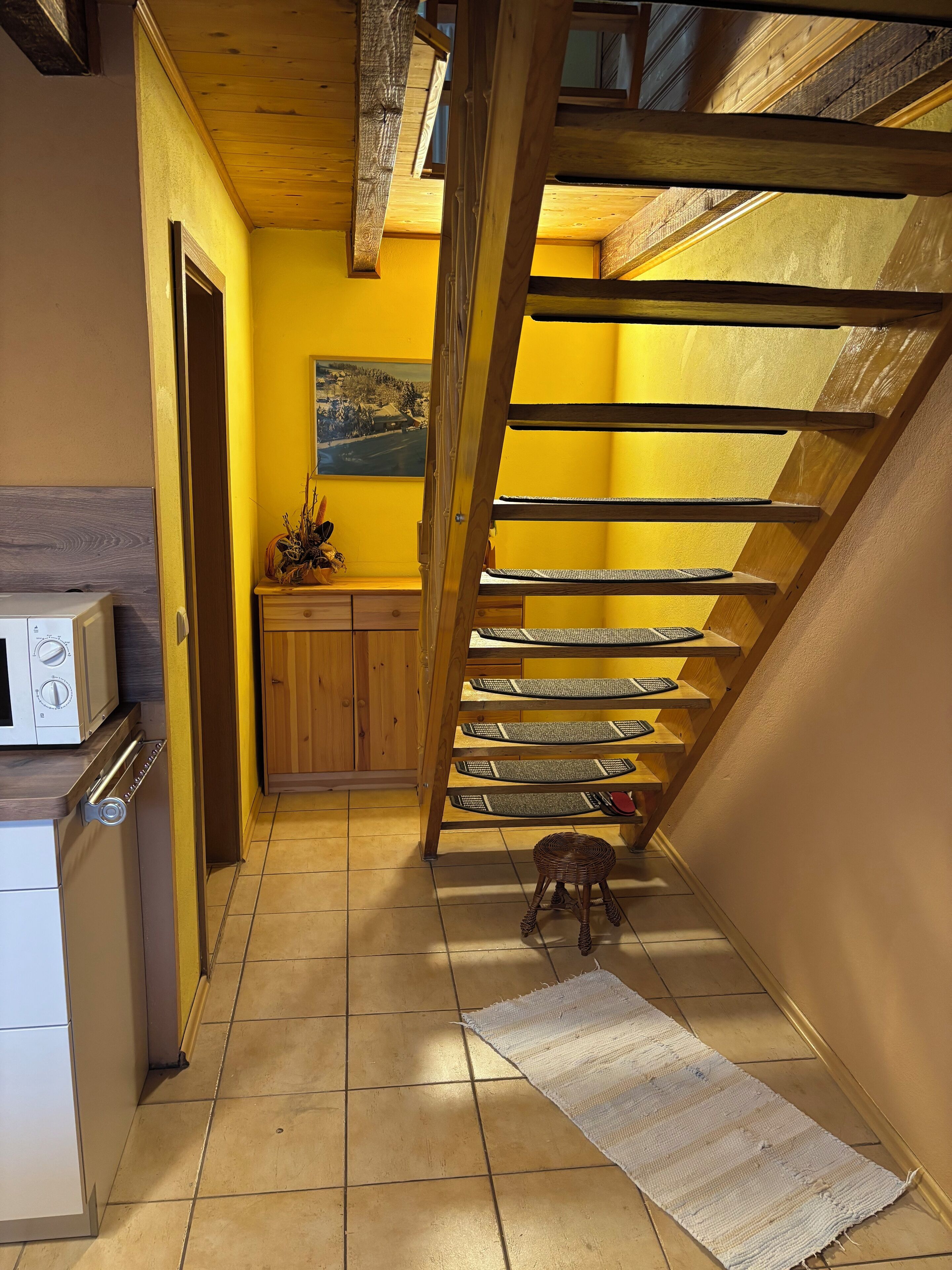 Una cocina con una escalera de madera que sube a una zona superior.