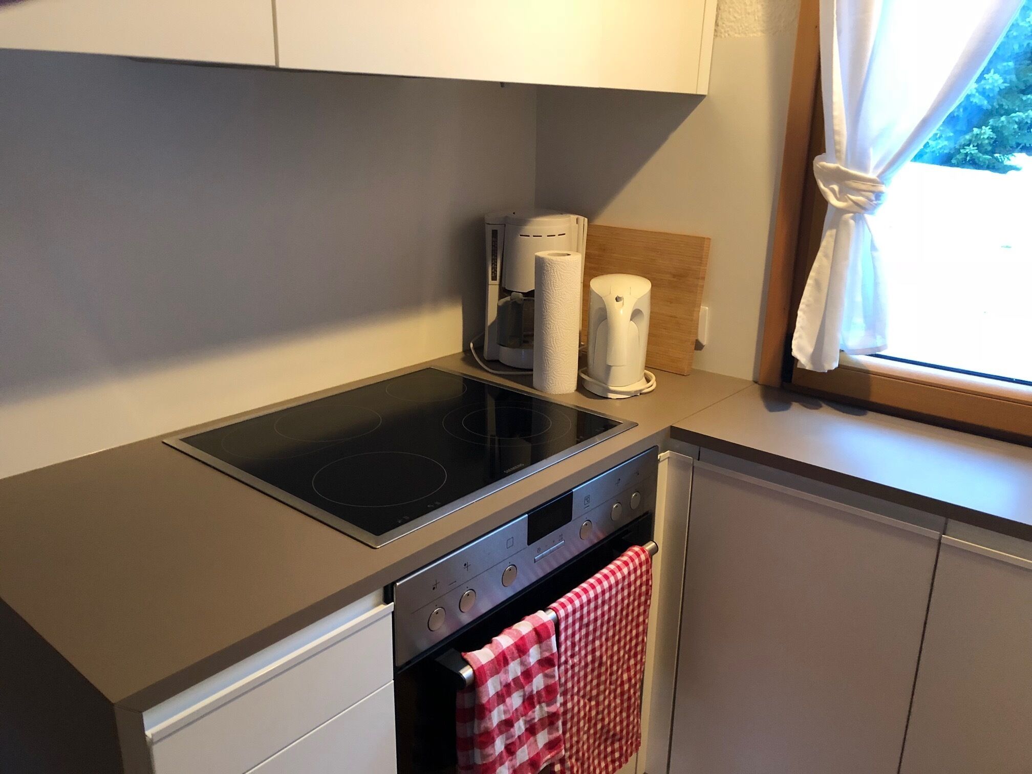 A compact kitchen with a built-in stovetop, a coffee maker, and a towel hanging on the oven door.