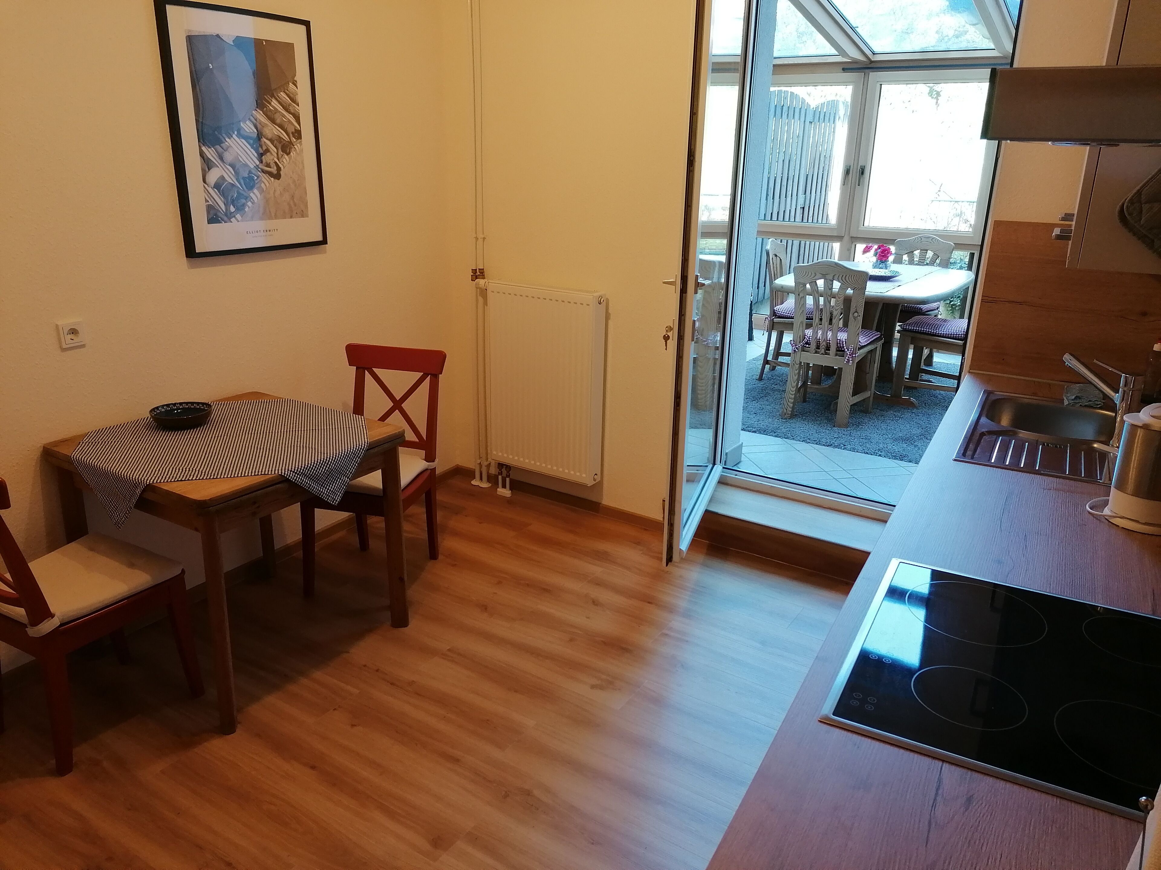 Une cuisine compacte avec un coin repas, un radiateur et une vue sur une terrasse extérieure.