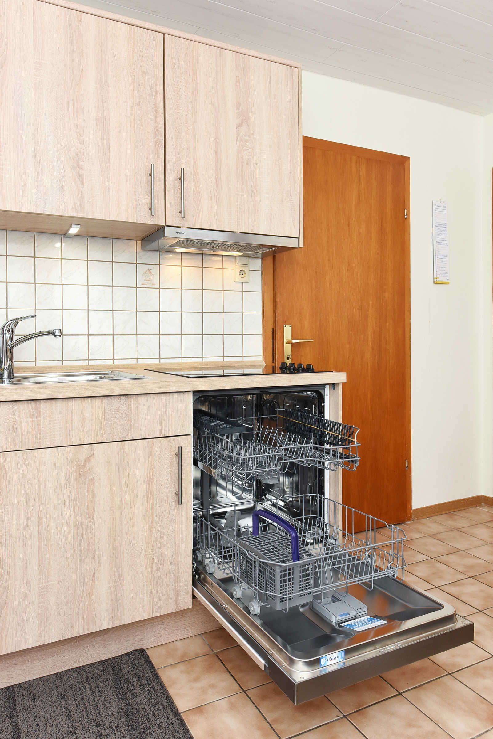 A kitchen with wooden cabinets, a built-in dishwasher, and a stainless steel sink.
