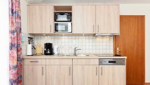 Eine Küche mit Holzausstattung, einer Mikrowelle, einem Toaster, einer Spüle und einem Geschirrspüler.