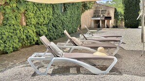 Des fauteuils de jardin avec un auvent, un chemin de gravier et un mur recouvert de lierre.