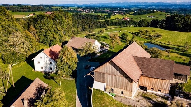 Paisaje rural con un granero, una casa blanca y una carretera.