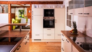 Una cocina moderna con armarios blancos, horno integrado y encimera de madera.