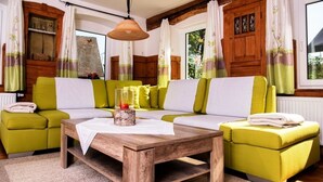 Una sala de estar acogedora con una mesa de centro de madera, sofás verdes y un mueble de madera.