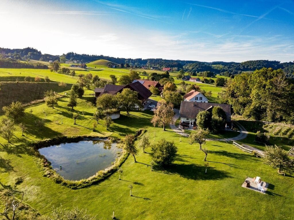 Ländliche Landschaft mit Häusern, einem Teich und blauem Himmel.