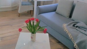 A living room with a sofa, a dining table, and a coffee table with a vase of flowers. - Apartment water lily Remseck (Remseck am Neckar)
