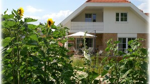 A two-story house with a sloped roof, a balcony, and a patio area with outdoor furniture. - Apartment water lily Remseck (Remseck am Neckar)