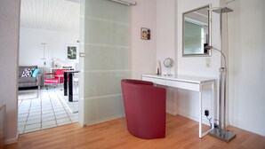 A modern bathroom with a white vanity, a red chair, and a large mirror. - Modern, bright and quiet apartment in the heart of the Black Forest (Sankt Märgen)