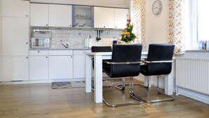 Eine moderne Küche mit weißen Schränken, einer weißen Arbeitsplatte, einer Mikrowelle und zwei schwarzen Stühlen.