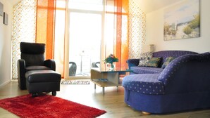 Ein Wohnzimmer mit einem schwarzen Sessel, einem blauen Sofa und einem roten Teppich.