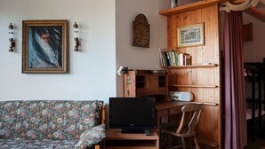 Un salón acogedor con un sofá floral, un mueble de televisión de madera, una estantería y un aparador de madera.