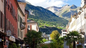 Una calle estrecha flanqueada por edificios, con una montaña al fondo y cielo despejado.