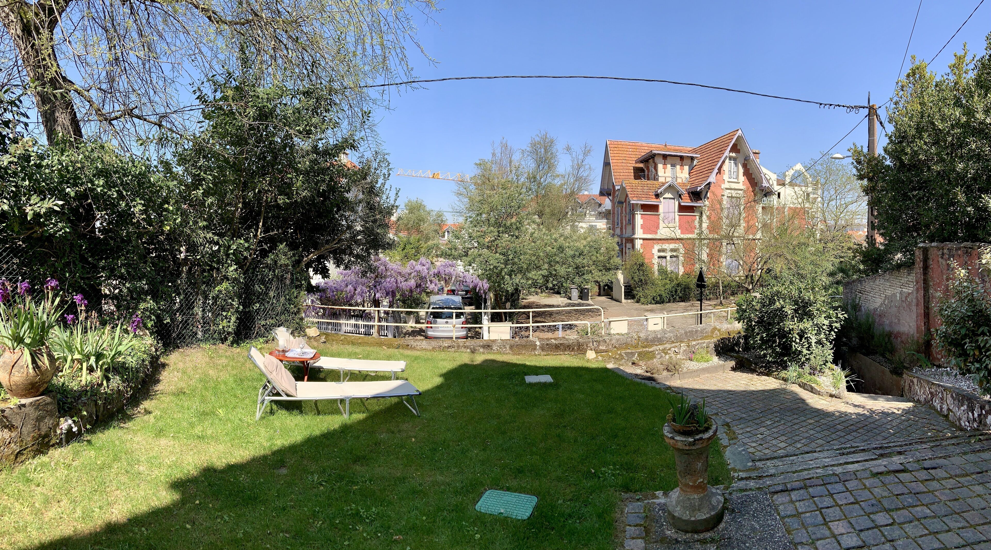 Un jardin bien entretenu, avec une pelouse, une table et des chaises, ainsi qu’une variété de plantes et de fleurs.