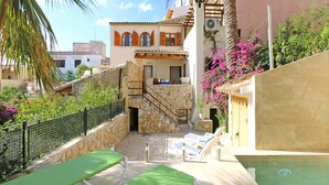 Un’area piscina con lettini, una scala in pietra e un edificio con finestre ad arco e un balcone.