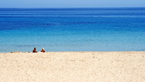 Una spiaggia con acqua cristallina e una battigia sabbiosa.
