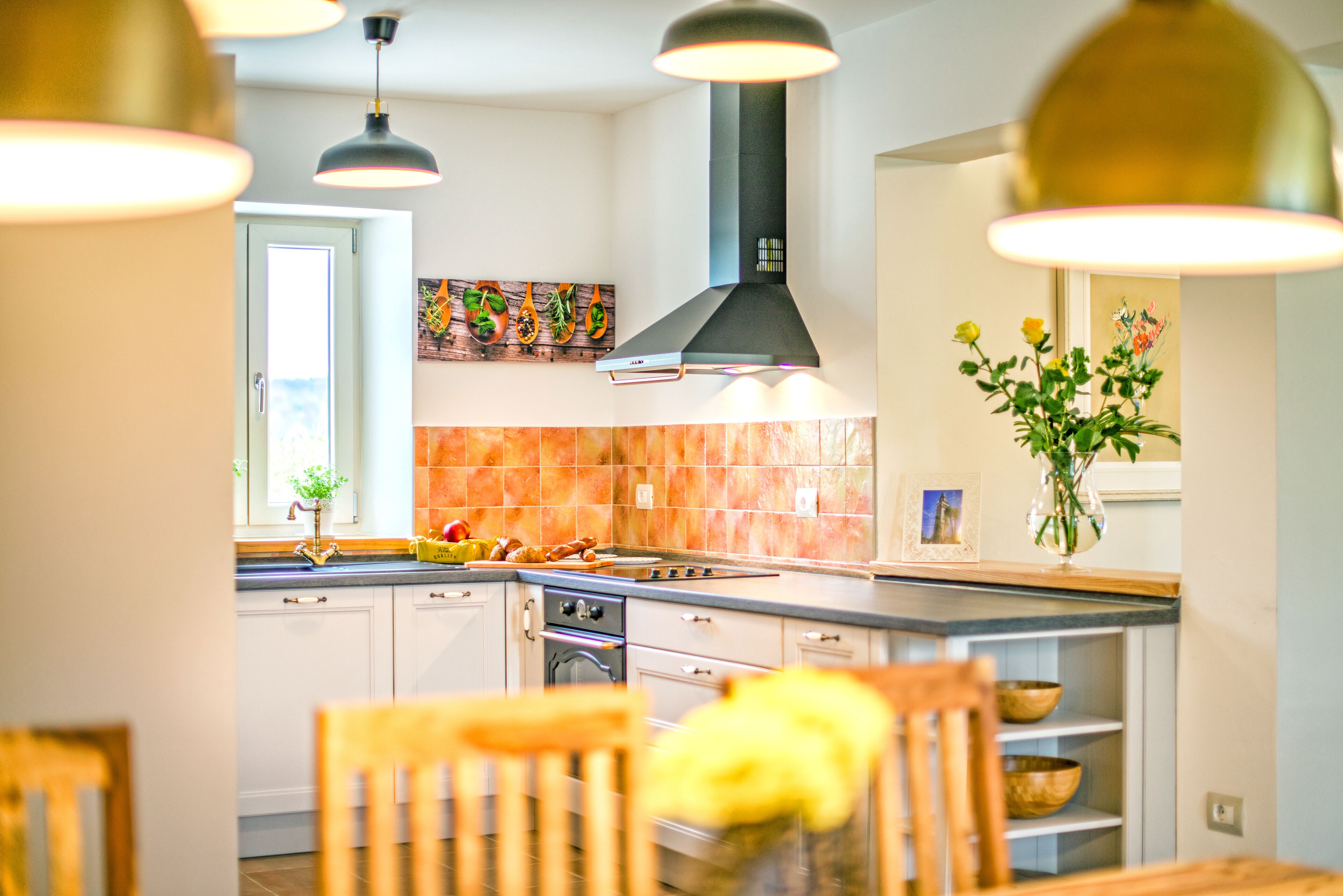 A modern kitchen with white cabinets, a large island, and a black range hood.